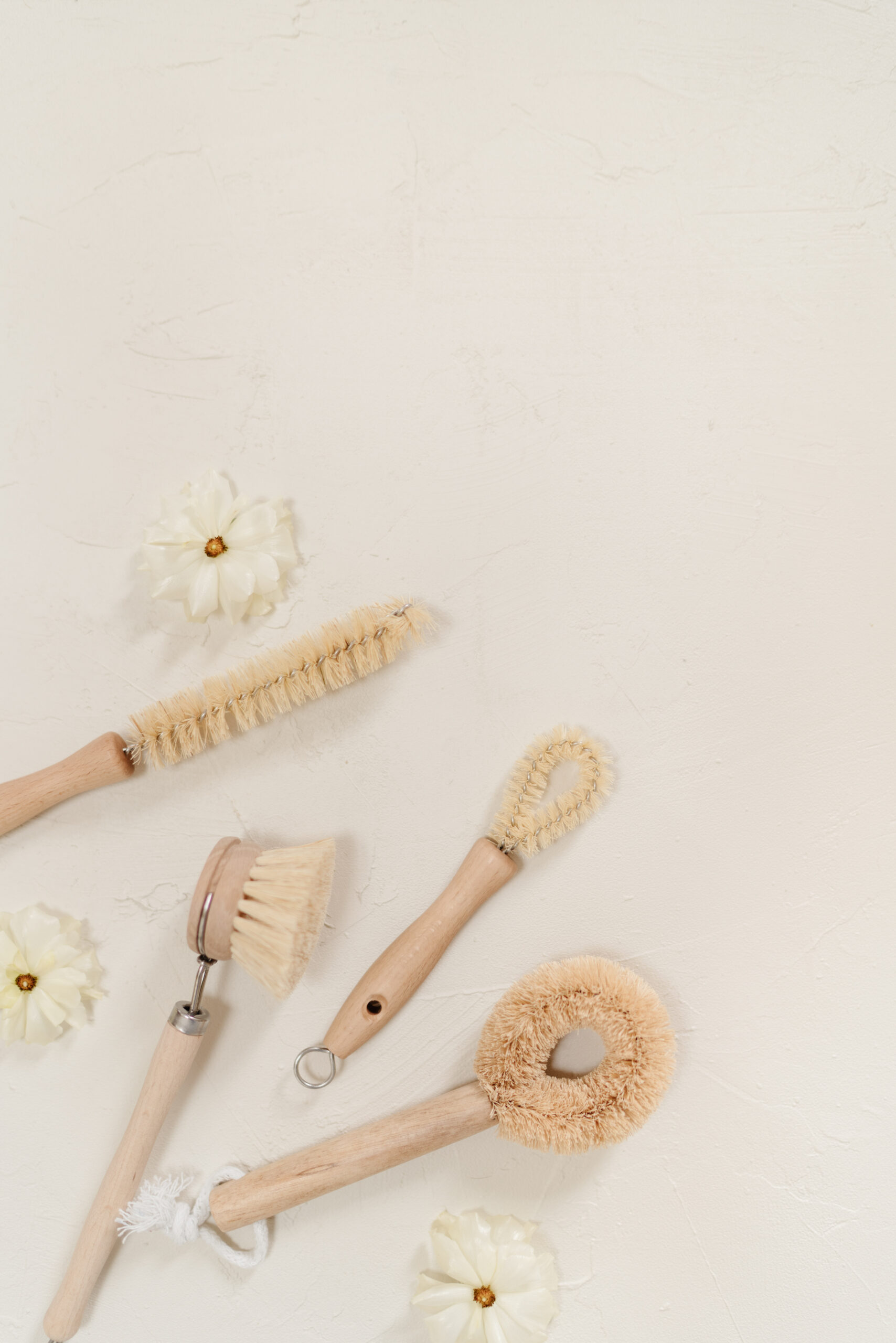 cleaning brushes and supplies with white flowers around them for small business owners spring cleaning