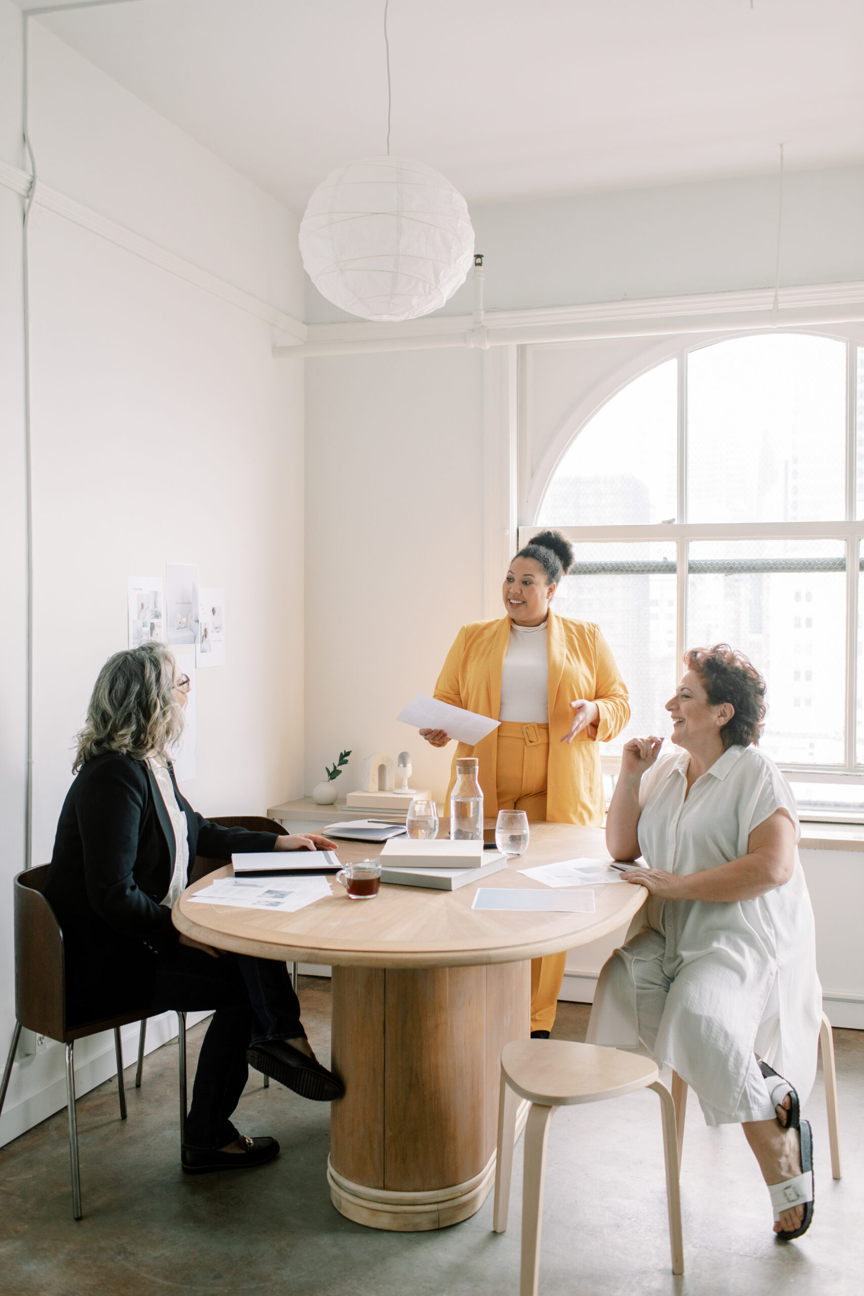 three women sitting around a table working and talking